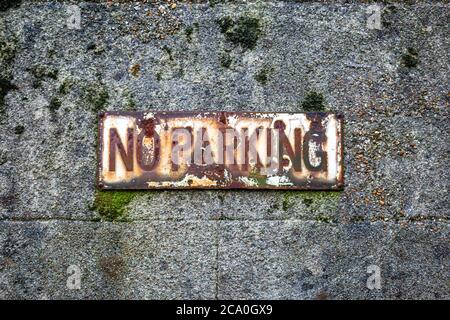Ein altes verwittertes No Parking Schild an der Seite eines Gebäudes Stockfoto