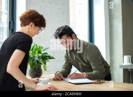 Zwei Geschäftsleute diskutieren das Treffen am Tisch mit Dokumenten und schreiben Notizen Stockfoto