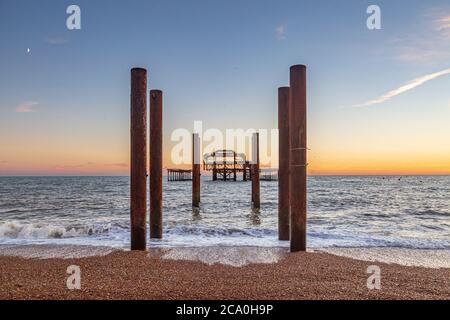 Brightons ikonischer West Pier bei Sonnenuntergang, mit dem Pebble Beach im Vordergrund Stockfoto