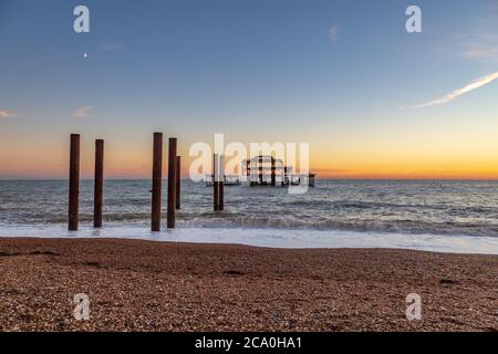 Brighton's West Pier bei Sonnenuntergang, mit dem Kiesstrand im Vordergrund Stockfoto