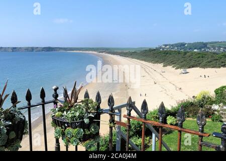 Urlauber tupfen den breiten Sand von South Beach in Tenby, Wales Stockfoto