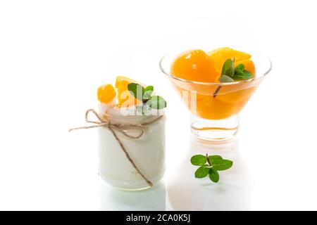 Hausgemachter süßer Joghurt mit eingelegten Pfirsichscheiben in einem Glas isoliert auf weißem Hintergrund Stockfoto