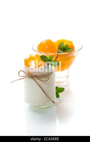 Hausgemachter süßer Joghurt mit eingelegten Pfirsichscheiben in einem Glas isoliert auf weißem Hintergrund Stockfoto