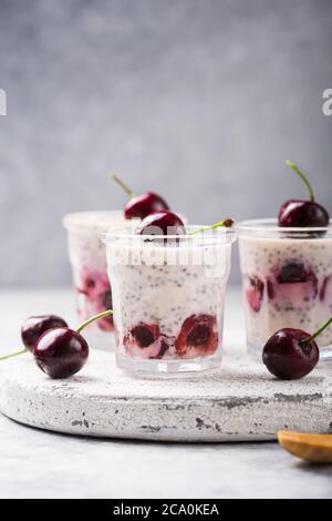 Chia Pudding mit Kirschbeeren, Naturjoghurt, in einem Glas auf einer grauen Oberfläche. Selektiver Fokus. Gesunde Nachtisch, richtige Ernährung, super Essen. Stockfoto