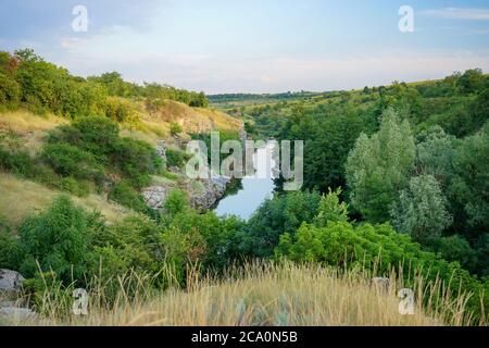 Hügel mit Bäumen und ein Feld in den Strahlen der Abendsonne Stockfoto