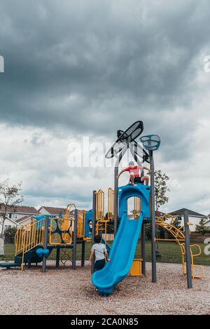 Jungen spielen auf einer Spielstruktur auf einem Spielplatz am bewölkten Sommertag. Stockfoto