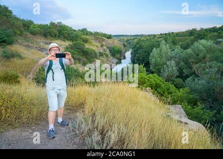 Guy macht ein Selfie während der Fahrt durch den Canyon. Typ mit Rucksack und blauem T-Shirt Stockfoto