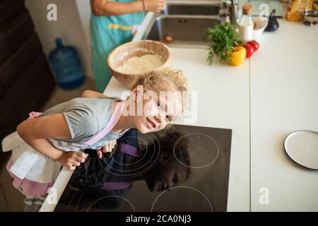 Zwei Blondinen kochen in der Küche. Nette kleine weibliche Köchin Blick auf Kamera kochen in der Küche, Draufsicht. Stockfoto