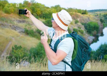 Guy macht ein Selfie während der Fahrt durch den Canyon. Typ mit Rucksack und blauem T-Shirt Stockfoto