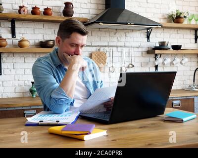 Junger Mann arbeitet aus der Ferne mit Finanzdokumenten. Arbeiten Sie von zu Hause aus. Stockfoto