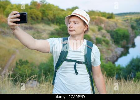 Guy macht ein Selfie während der Fahrt durch den Canyon. Typ mit Rucksack und blauem T-Shirt Stockfoto