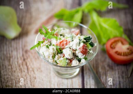 Frischer Quark-Salat mit Gurken und Tomaten mit Kräutern in einer Schüssel auf dem Tisch Stockfoto