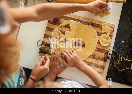 Krauses blondes Haar Mutter und ihre entzückende Tochter mit lockigen blonden Haaren Schneiden Formen aus Teig für Cookies in der Küche. Kleines Mädchen mit m Stockfoto