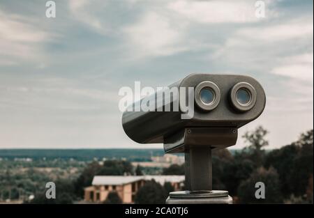 Touristenteleskop mit Blick auf den Stadtpark. Metallisches Beobachtungsfernglas Nahaufnahme mit linkem Kopierraum. Abgeschwächt Stockfoto