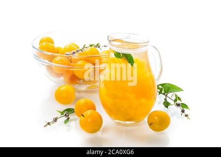 Süßes gekochtes Kompott in einem Glasdekanter aus reifen gelben Kirschpflaumen, auf einem weißen Teller Stockfoto