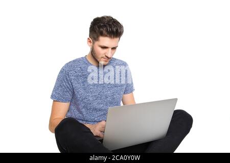 Teenager Nerd isoliert vor Laptop-Typen verschiedene denkt an seinen Computer, während im Boden mit gekreuzten Beinen sitzen und von etwas genietet Stockfoto