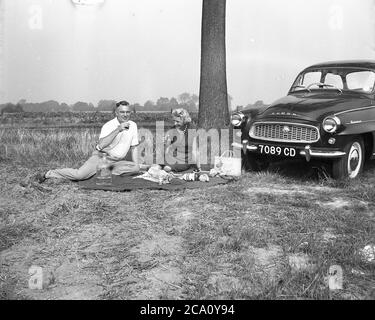 1960, historisch, ein britisches Paar, das durch Frankreich fuhr. Zusammen auf einer Decke sitzend, einen Becher französischen Weinrot und ein Picknick am Straßenrand neben ihrem Skoda Octavia Auto, einem kleinen Familienauto aus der Zeit des tschechoslowakischen Autoherstellers AZNP in Mlada Boleslav von 1969 bis 1971. Es wurde Octavia genannt, da es das achte Auto des tschechischen Automobilherstellers Skoda Auto war. Stockfoto