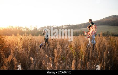 Seitenansicht der Familie mit kleiner Tochter auf einem Spaziergang in der herbstlichen Natur. Stockfoto