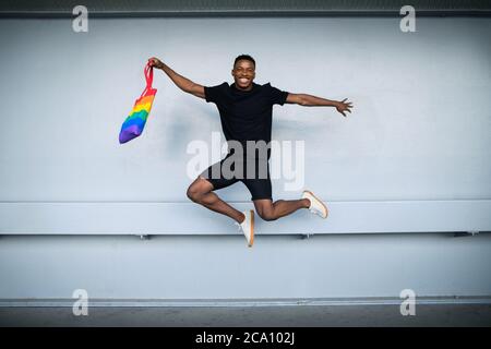 Junger schwarzer Mann springt gegen weiße Wand Hintergrund, schwarz lebt Materie Konzept. Stockfoto