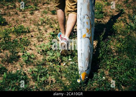 ODESSA, UKRAINE - MAI 20 2015: Junger Surfer mit altem Surfbrett ist auf dem Weg zum Strand Stockfoto