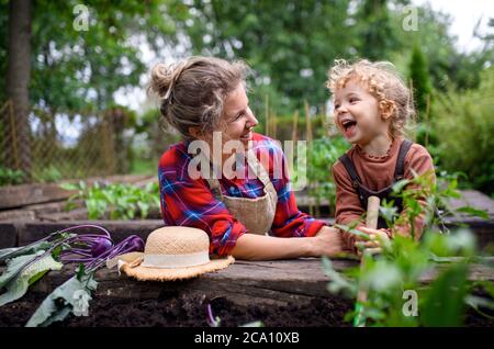 Mutter mit kleiner Tochter im Garten auf dem Bauernhof, Anbau von Bio-Gemüse. Stockfoto