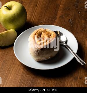 Vegane Zimtrollen mit Apfel auf einem Holzbrett. Stockfoto