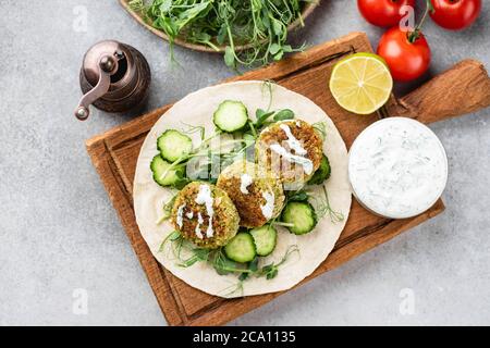 Vegane Falafel mit Gemüse und Tzatziki-Sauce auf Holzbrett, Draufsicht. Arabisches Essen Stockfoto