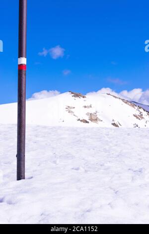 Metallstange mit einer GR-Markierung auf dem Schnee. Stockfoto