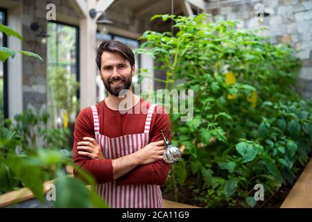 Porträt eines Gärtners, der im Gewächshaus steht und die Kamera anschaut. Stockfoto