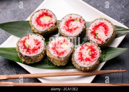 Sushi-Brötchen aus Reis, geräuchertem Aal, Frischkäse und fliegender Fischrohe Set heiße Brötchen mit Avacado, Lachs, Frischkäse, Algen, Sojasauce, Ingwer auf Stockfoto