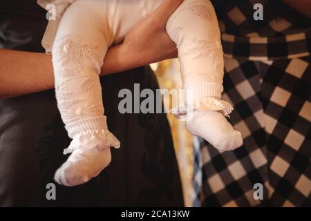 Nahaufnahme der Füße des Babys in den Händen der Mutter. Taufe in der orthodoxen christlichen Kirche Stockfoto