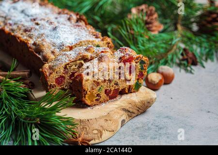 Traditionelle Weihnachts-Obstkuchen auf einem Holzbrett in festlicher Dekoration, dunkler Hintergrund. Stockfoto