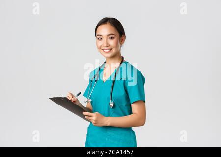 Mitarbeiter im Gesundheitswesen, Virenprävention, Quarantänekampagne Konzept. Lächelnd freundliche Ärztin, Krankenschwester in Scrubs schreiben dorn Ergebnisse Analyse bei Stockfoto