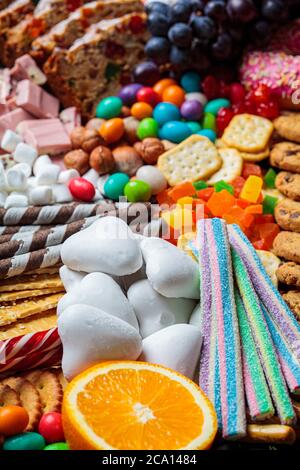 Weihnachts Süßigkeiten Platte. Weihnachtskuchen, Süßigkeiten, Schokolade, Zuckerrohr, Kekse, Obst auf schwarzem Tablett Stockfoto