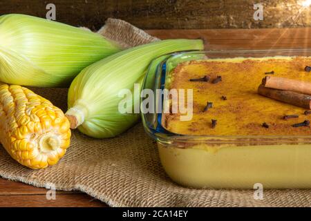 Canjica Curau. Typische brasilianische Junina Party Süßigkeiten. Maiskolben. Rustikaler Holzhintergrund. Brasilianisches Dessert Stockfoto