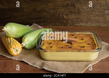 Canjica Curau. Typische brasilianische Junina Party Süßigkeiten. Maiskolben. Rustikaler Holzhintergrund. Brasilianisches Dessert Stockfoto