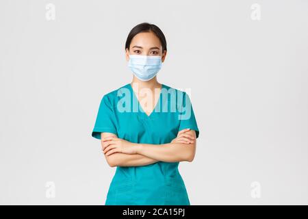 Covid-19, Coronavirus-Krankheit, Konzept für Mitarbeiter im Gesundheitswesen. Lächelnd zuversichtlich asiatische Ärztin, Arzt, der Check-up, das Tragen von Peelings und medizinische Stockfoto