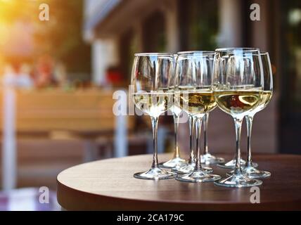 Weißweinprobe auf der Terrasse des Weinguts, Ausgießen von kaltem trockenem Wein in Gläsern im Freien an sonnigen Tag Stockfoto