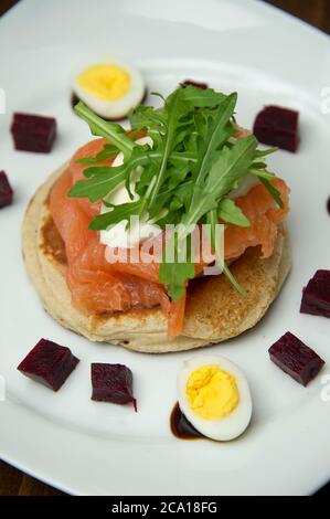 Geräucherter Lachs, Mozarella und Rucola auf einem Muffin, mit Rote Bete, gekochtem Ei und Rote Bete Püree Stockfoto