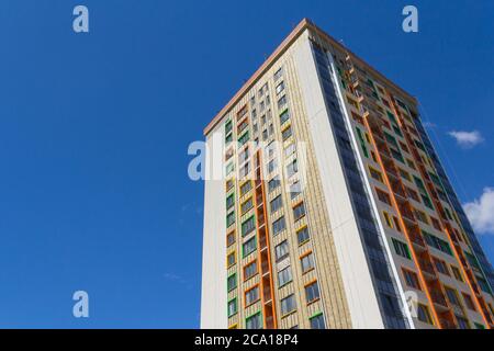 Ein Hochhaus vor blauem Himmel. Ein neues Hochhaus mit farbenfroher Fassade. Stockfoto