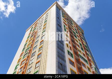 Ein Hochhaus vor blauem Himmel. Ein neues Hochhaus mit farbenfroher Fassade. Stockfoto