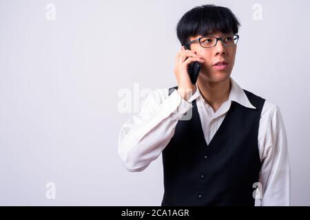 Porträt von jungen schönen asiatischen Geschäftsmann im Gespräch am Telefon Stockfoto