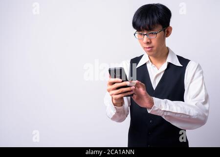 Porträt der jungen gut aussehenden Asiatische Geschäftsmann mit Mobiltelefon Stockfoto