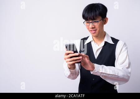 Portrait von glücklich junge gut aussehende asiatische Geschäftsmann mit Telefon Stockfoto