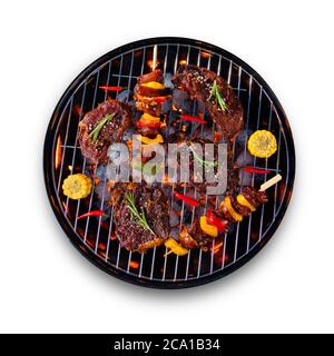 Frische rohe Rindersteaks und Spieße mit Gemüse auf dem Grill platziert, isoliert auf weißem Hintergrund. Kochen, Zubereitung und Grillzubehör. Stockfoto
