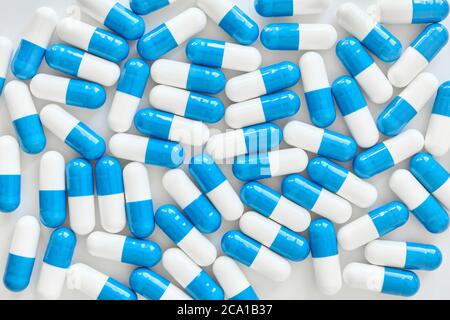 Nahaufnahme von vielen blauen und weißen Kapseln auf weißem Hintergrund. Stockfoto