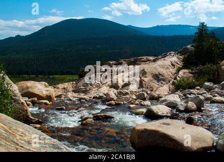 Blick auf einen Bach im Schwemmklüfter mit Bergen im Hintergrund, Rocky Mountain National Park, Colorado USA Stockfoto