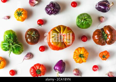 Lebensmittelzusammensetzung. Verschiedene bunte Bio-Tomaten und Pfeffer Gemüse auf weißem Hintergrund. Draufsicht. Flach legen Stockfoto