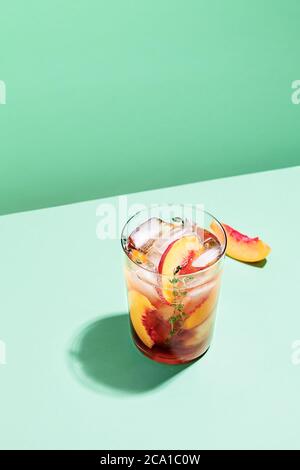 Sekt kalt brauen Pfirsich Tee mit Thymian im Glas auf grünem Papier Hintergrund Draufsicht. Erfrischendes sommerliches alkoholfreies Getränkekonzept Stockfoto