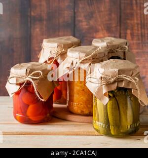 Eingelegtes Bauerngemüse in Gläsern auf einem hölzernen Hintergrund. Fermentierte Trendfutter. Haus rustikalen Stil. Stockfoto